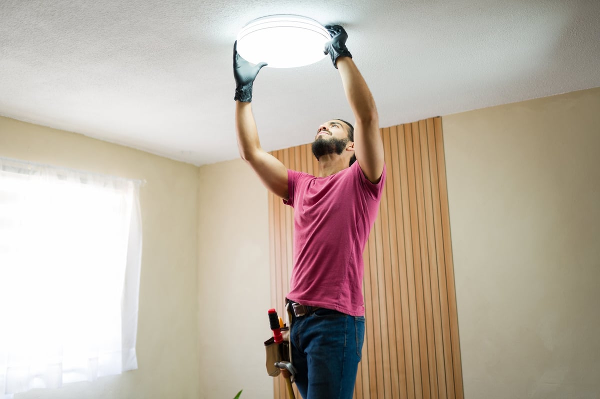 Electricista instalando una lámpara de techo en una casa moderna